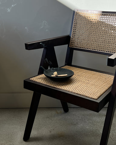 The image depicts Takashi Dining Chair - Dark Brown with a plate resting on it. The chair is captured from various angles, highlighting its woven texture and curved form. The plate, which appears to hold some kind of food, is also shown in different positions on the chair. The background of the image is not visible, allowing the viewer to focus solely on the details of the chair and plate. The overall impression is one of relaxation and comfort, evoking images of lazy afternoons spent lounging in a cozy corner with a good book and a snack.