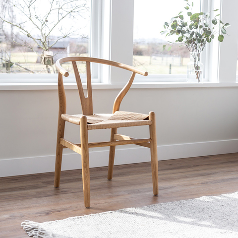 The photograph captures a wooden chair in front of a window, with various perspectives and close-ups of the same scene. The chair is made of polished wood and has a simple yet elegant design, with a straight backrest and four legs. The window behind the chair is large and rectangular, with white frames that contrast with the dark wood. The view outside the window is not visible due to the brightness of the light coming through it. The lighting in the room is warm and cozy, creating a comfortable atmosphere. Different angles and distances capture different parts of the scene, but they all convey the same message of simplicity and elegance.