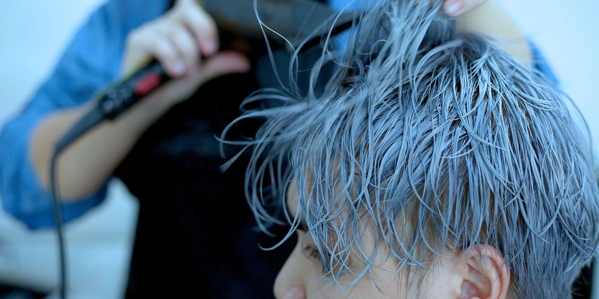 homme appliquant une teinture bleue sur ses cheveux
