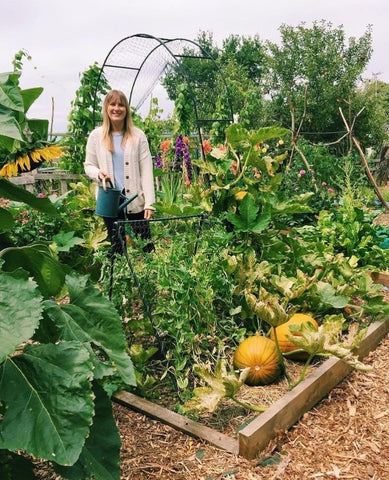 Emma in allotment, with squashes in a raised bed
