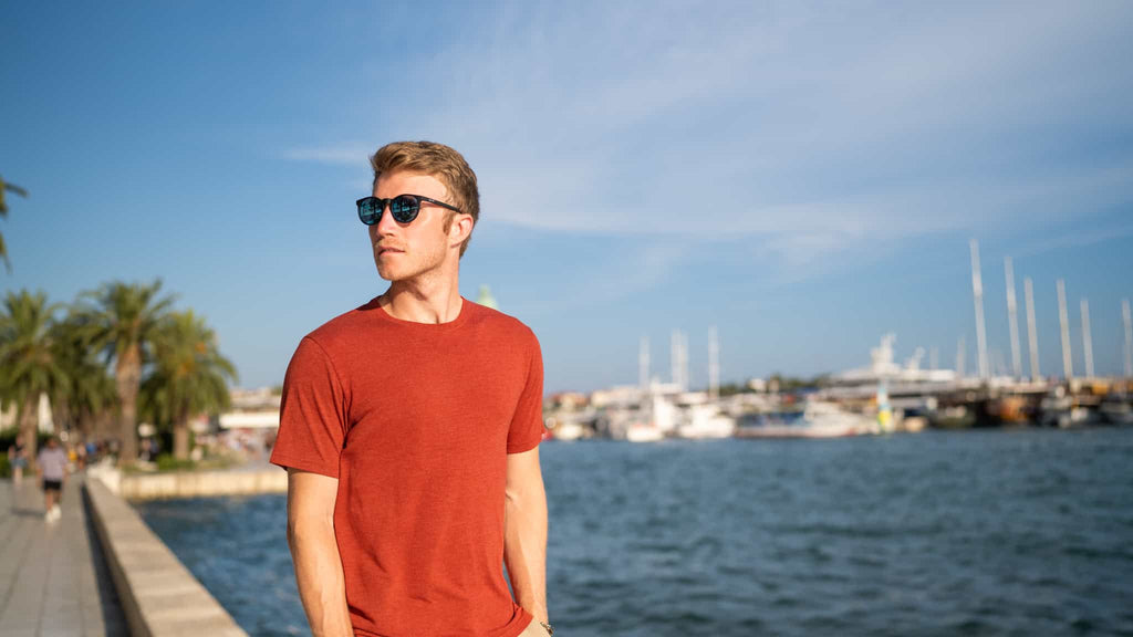 Man with sunglasses standing in a performance tee on the boardwalk in Croatia.