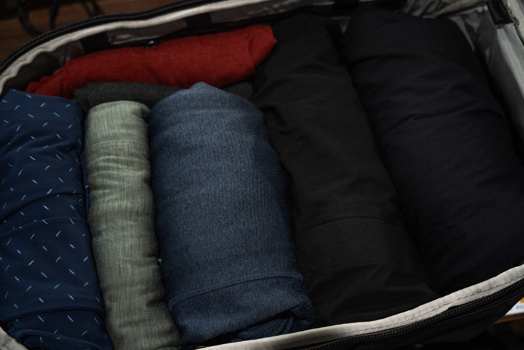 Multiple layers of rolled clothing in a travel backpack.
