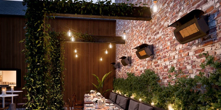 Wall mounted patio heaters over a long table in a commercial resturant type setting