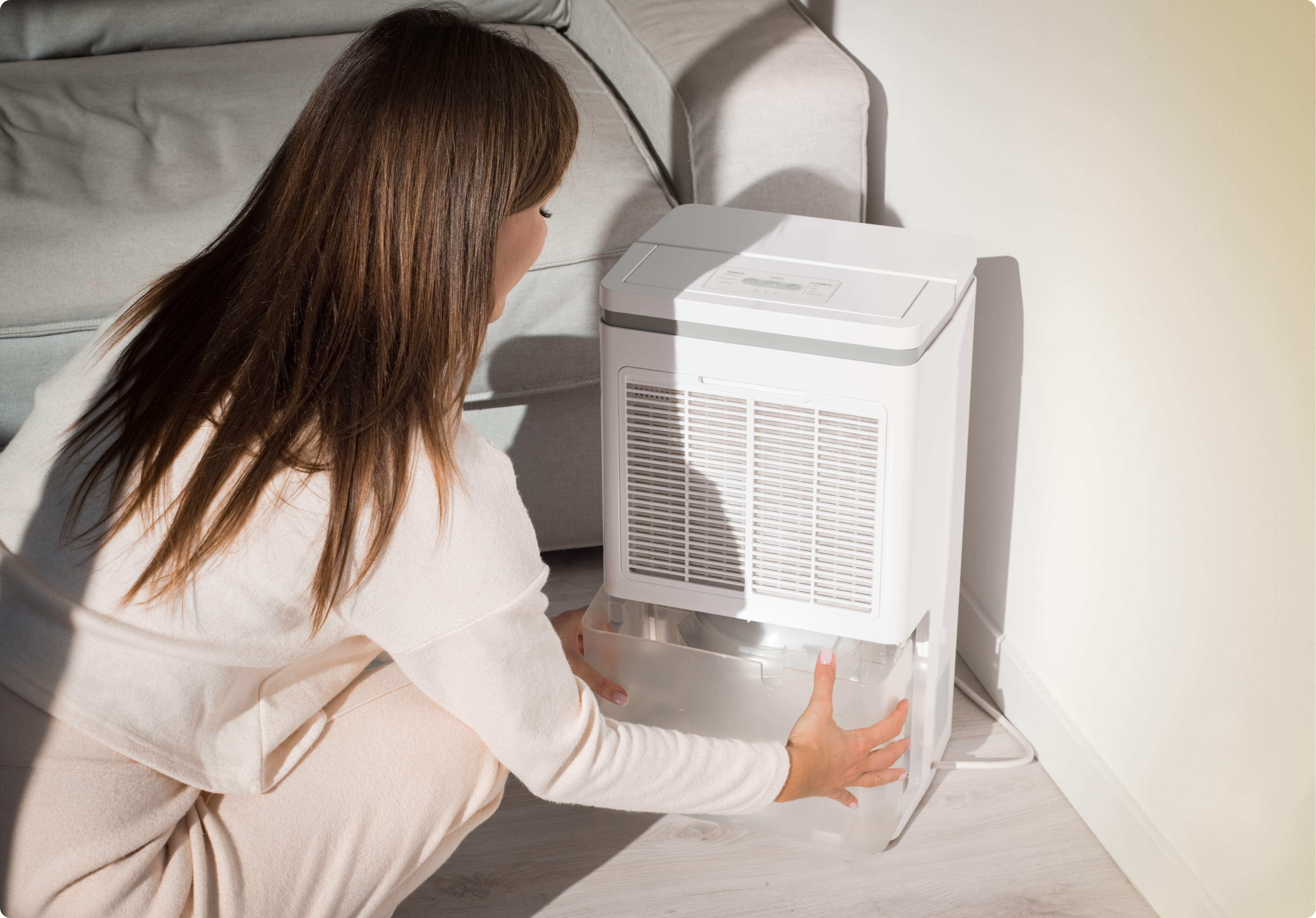 image of a hand holding a remote control pointing it at a portable air conditioning unit