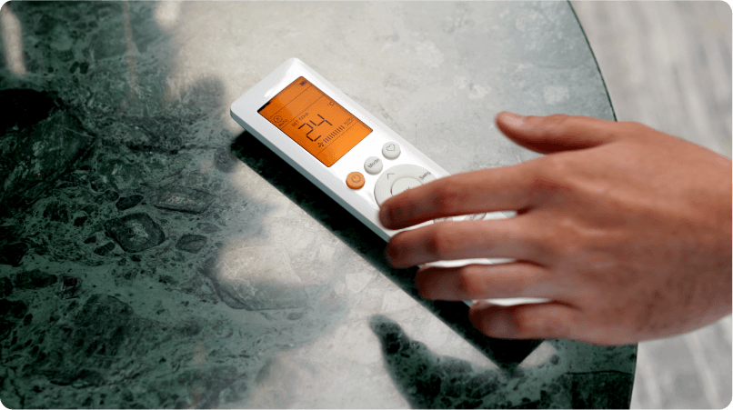 an image of a hand reaching for a remote control of an air conditioning unit