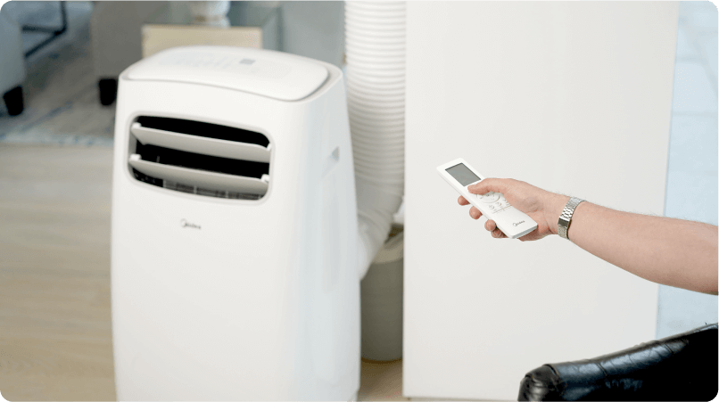 image of a hand holding a remote control pointing it at a portable air conditioning unit