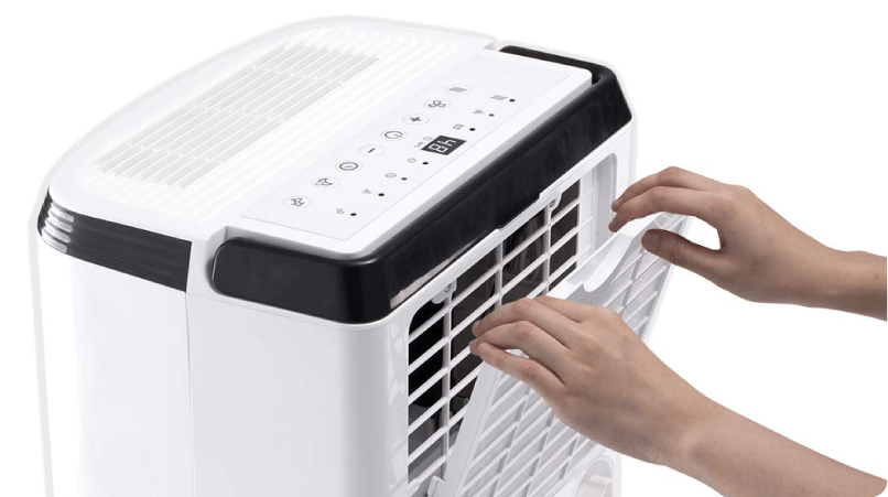 image of a hand holding a remote control pointing it at a portable air conditioning unit