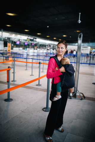 Mum carrying her child in a Tula baby carrier on an airport
