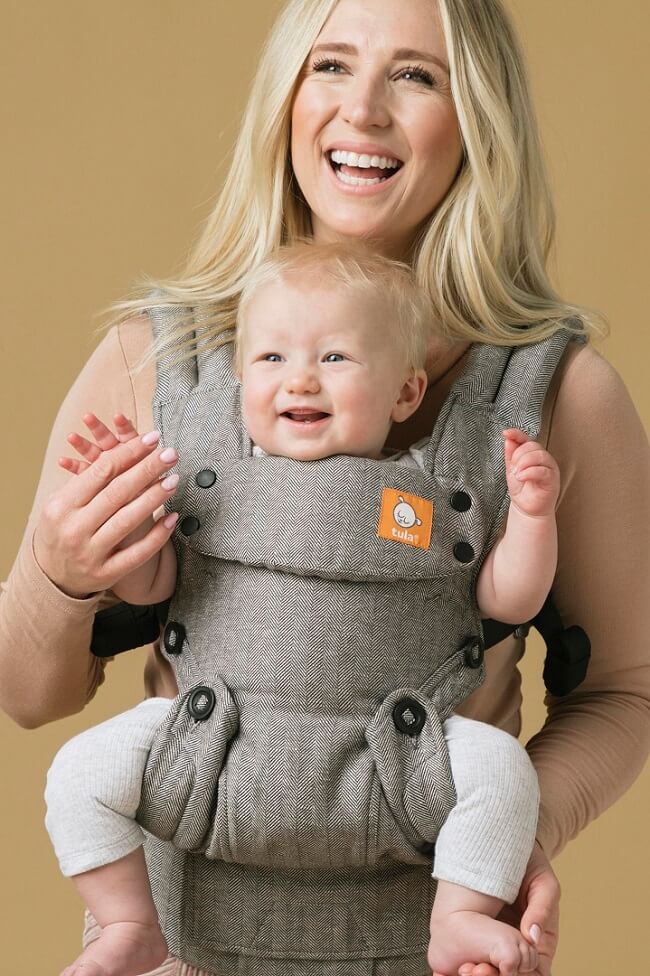 Close up of ergonomic outward facing baby carrier.