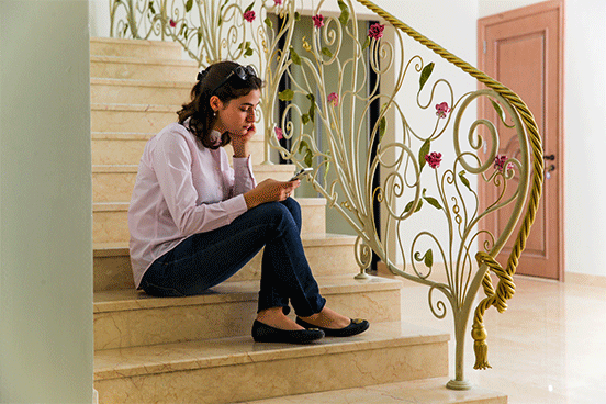 Young lady sits on the steps by a rose themed wrought iron handrail