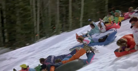 a group of people inner tube down a snowy hill