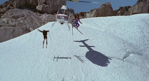 two skiiers jump out of a helicopter onto a snowy mountain