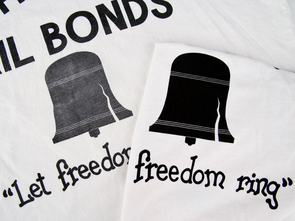 close up view of two chico's bail bonds t-shirts, one is aged with faded text and one is new with crisp black text