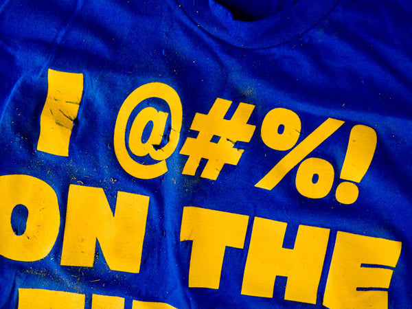 a blue t-shirt with yellow lettering that has been scratched with sandpaper