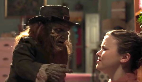 a creepy leprechaun talks to a young woman who looks scared