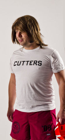 man with mullet haircut wears shorts and white t-shirt that says cutters on it