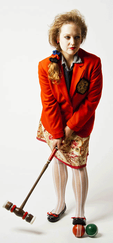 woman wearing red jacket, red floral skirt, and holding a croquet mallet