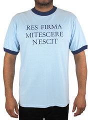 light blue t-shirt with navy blue neck band and arm bands.  Shirt says Res Firma Mitescere Nescit on the front.