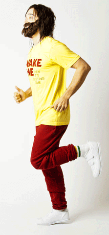 a man with brown hair and a brown beard wears a yellow t-shirt and red pants
