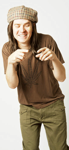 man with long hair wears backwards plaid cap, a brown t-shirt with a pot leaf on it, and green pants