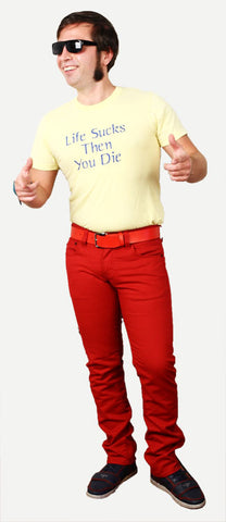 man with dark hair and long sideburns wears sunglasses, red pants, and a yellow shirt that says life sucks then you die