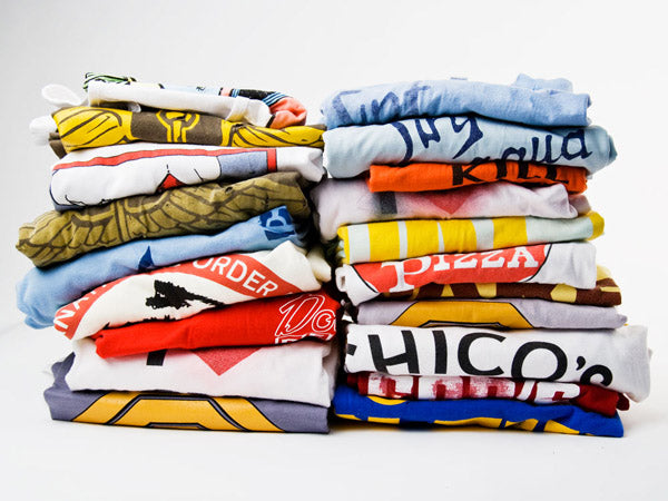 two stacks of folded t-shirts of all colors