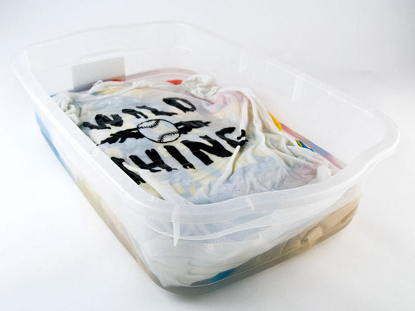 several t-shirts soaking in a clear plastic tub