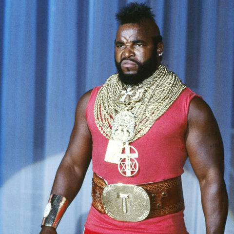 mr. t wearing a red tank top, a stack of gold necklaces, and a leather belt