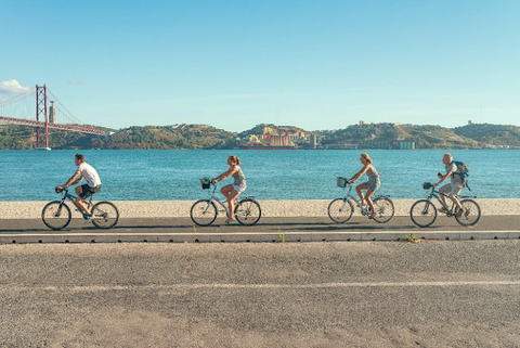 4 people cycling in front of the water