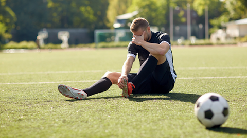 Football player sitting on pitch