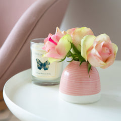 a handmade bud vase on a table with a candle