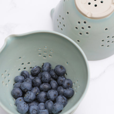 Handmade berry bowl in a duck egg blue glaze filled with blueberries