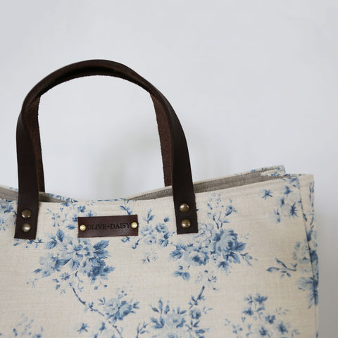 A close up of the leather handle of the handmade bag in Olive & Daisy fabric