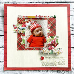 scrapbook page featuring photo of a newborn in a Christmas outfit. Page is embellished with Christmas-themed scrapbook supplies