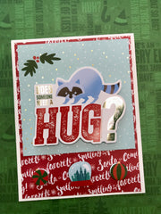 Does someone need a hug Christmas card made with Elf Craft Kit. Card features a die cut with an funny raccoon and the words: Does someone need a hug?