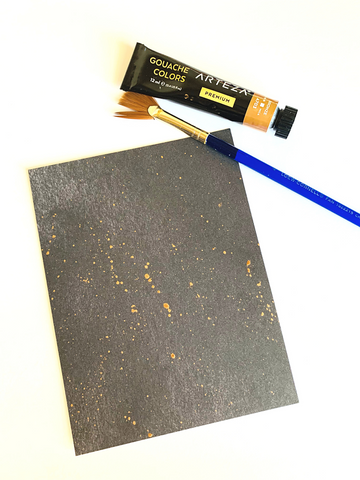 Black card base splattered with gold paint