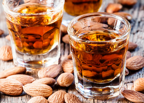 Two shot glasses of Amaretto Liqueur with almonds on a wood table