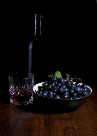 Bottle of Sloe Gin, glass of sloe gin, and bowl or sloe berries
