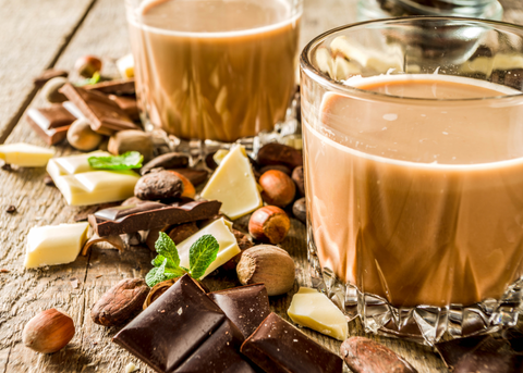 coffee flavored liqueurs in glass with chocolate and hazel nuts on table