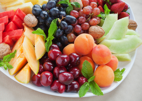 fruit platter with various fruits, nuts, and mint as garnish