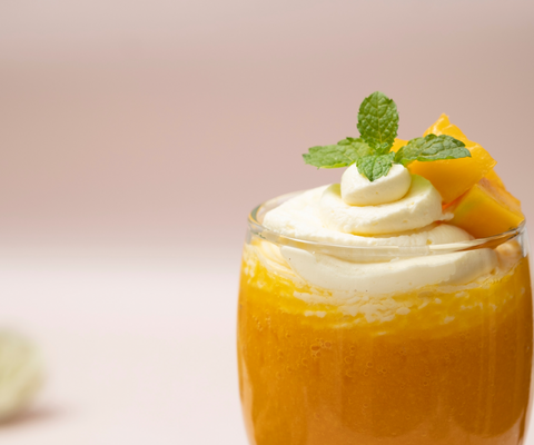creamsicle cocktail with whipped cream, cut fruit, and mint garnish