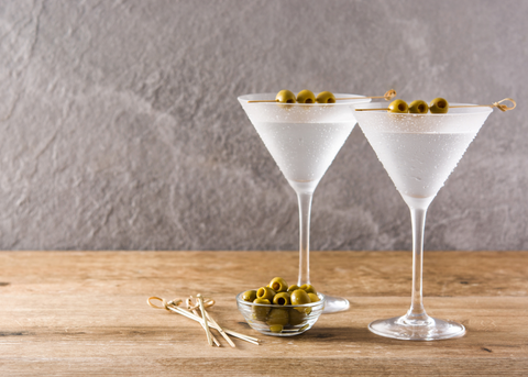 two dry martini cocktails with bowl of olives