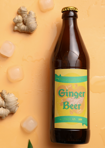 bottle of ginger beer with orange background with ginger and ice