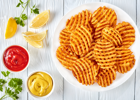 bowl of waffle fries with ketchup, mustard, and lemon wedges on the side