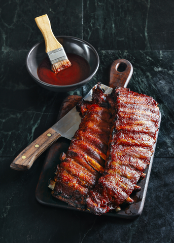Barbecue ribs with knife and side of sauce with brush