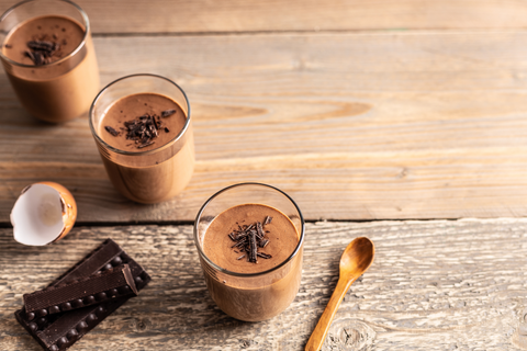 chocolate mouse with chocolate shavings, egg shells, spoon, and chocolate bar on table