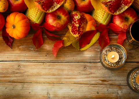 Harvest table with pumpkin, corn, fruits, and candle