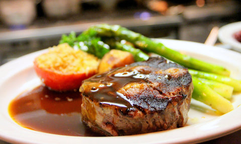 Meat marinated in coffee served on a plate with vegetables