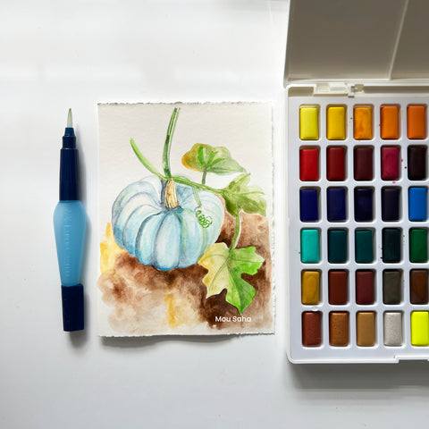 A watercolor blue pumpkin painting with a watercolor pan