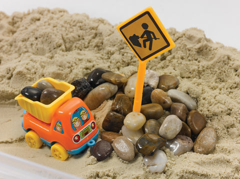 Sensory bin with sand, pebbles, and a dump truck